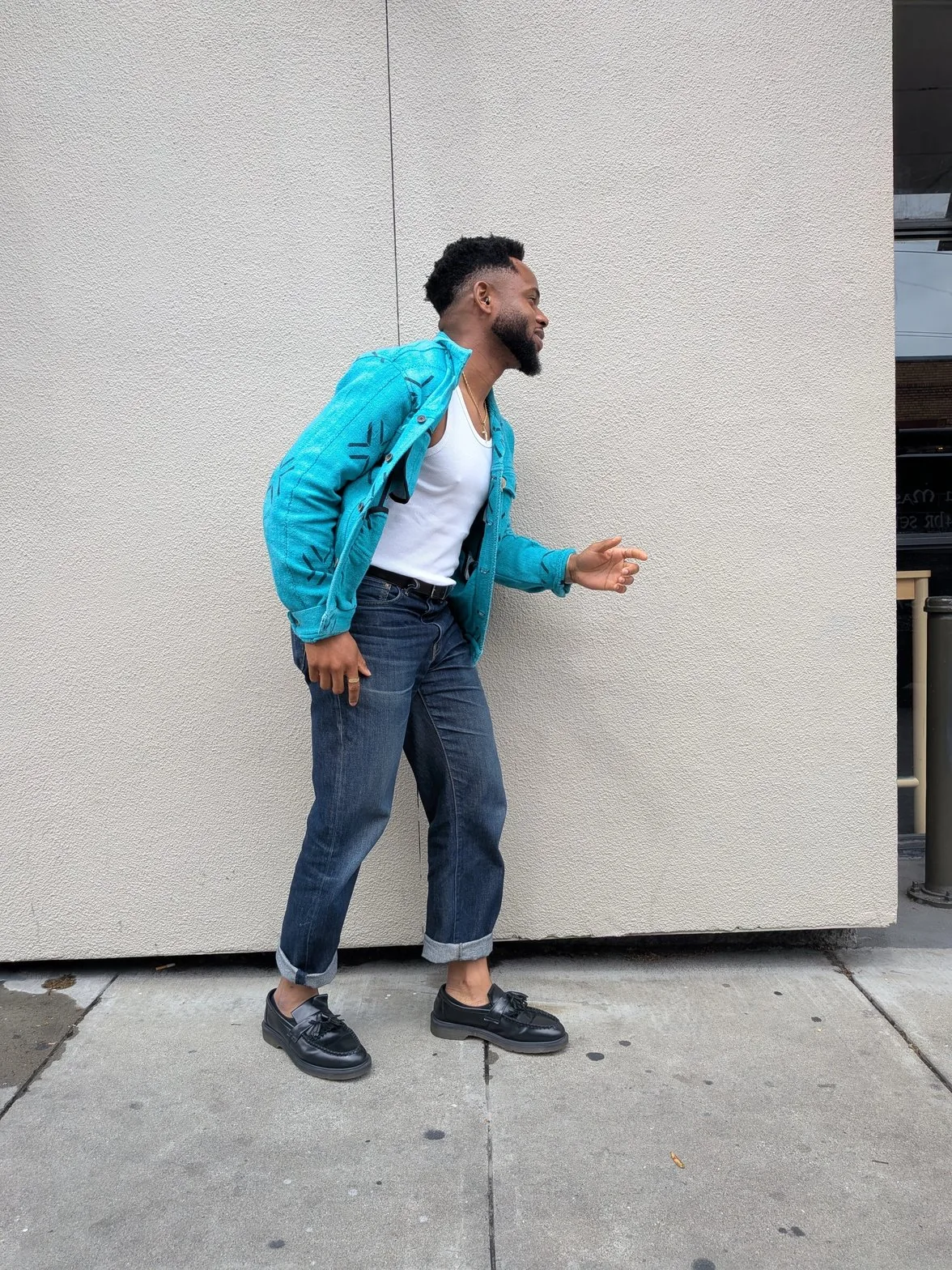 Chielo in profile, turquoise jacket open, arms extended