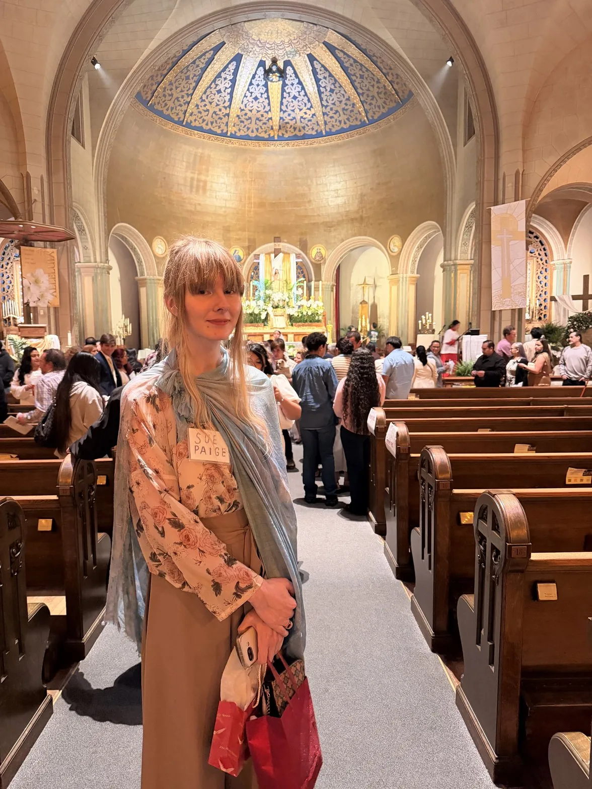 Sue standing in the cathedral aisle under a golden dome
