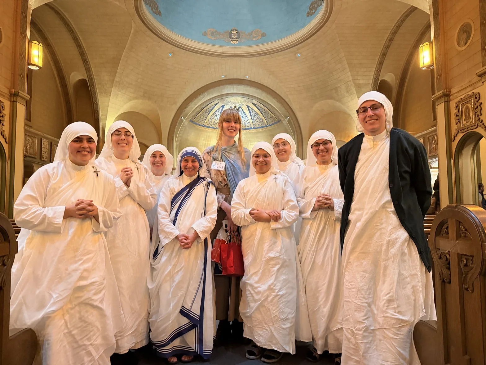 Sue surrounded by eight smiling Catholic sisters in the cathedral